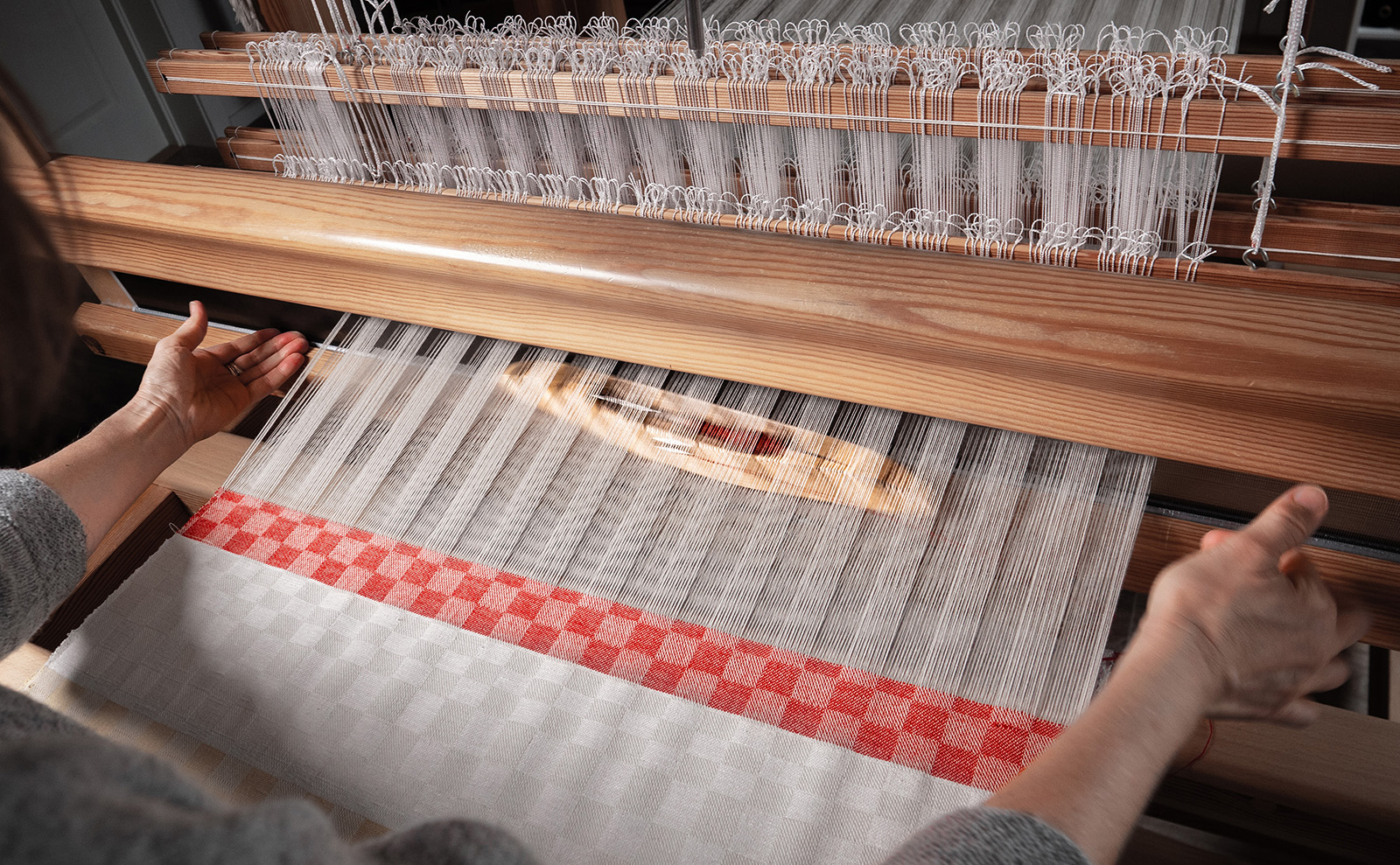 Håndvever Lise Skoug Obel ved veven. Hun leter fram og skaper nye stoffer i mønstre fra eldre tekstiler. Foto: Nilsson Cinematics